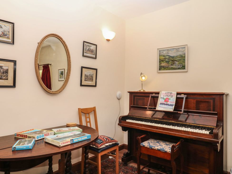 A sitting room with a piano and a table at Lukesland Wing Ivybridge