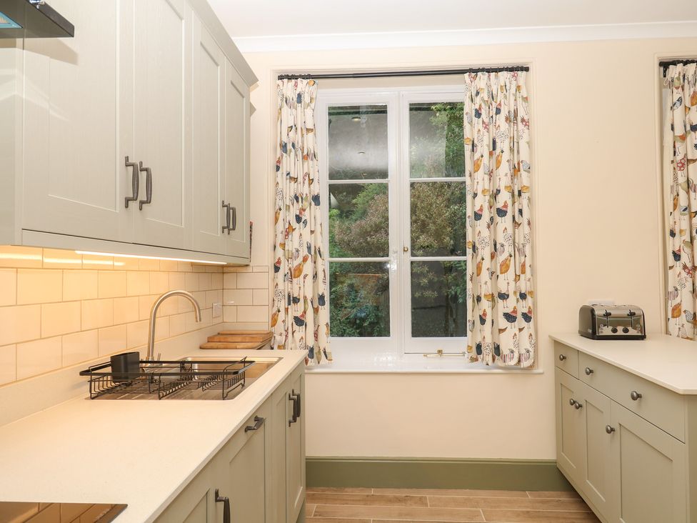 A kitchen with cabinets and a window at Lukesland Wing in Ivybridge