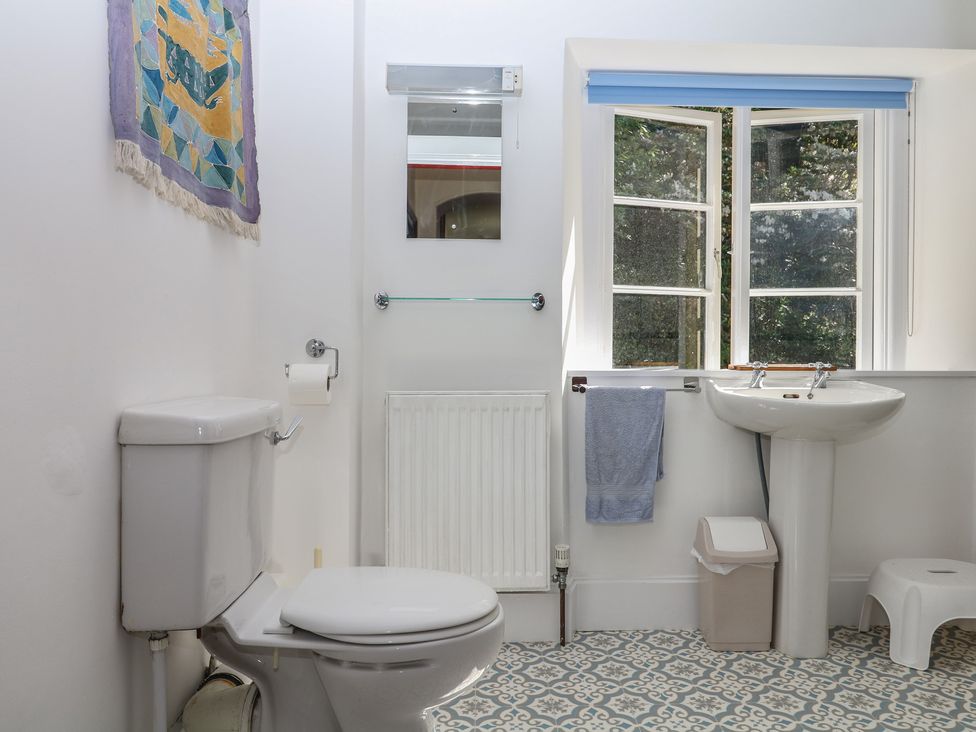 A bathroom with a toilet, sink, and window at Lukesland Wing in Ivybridge