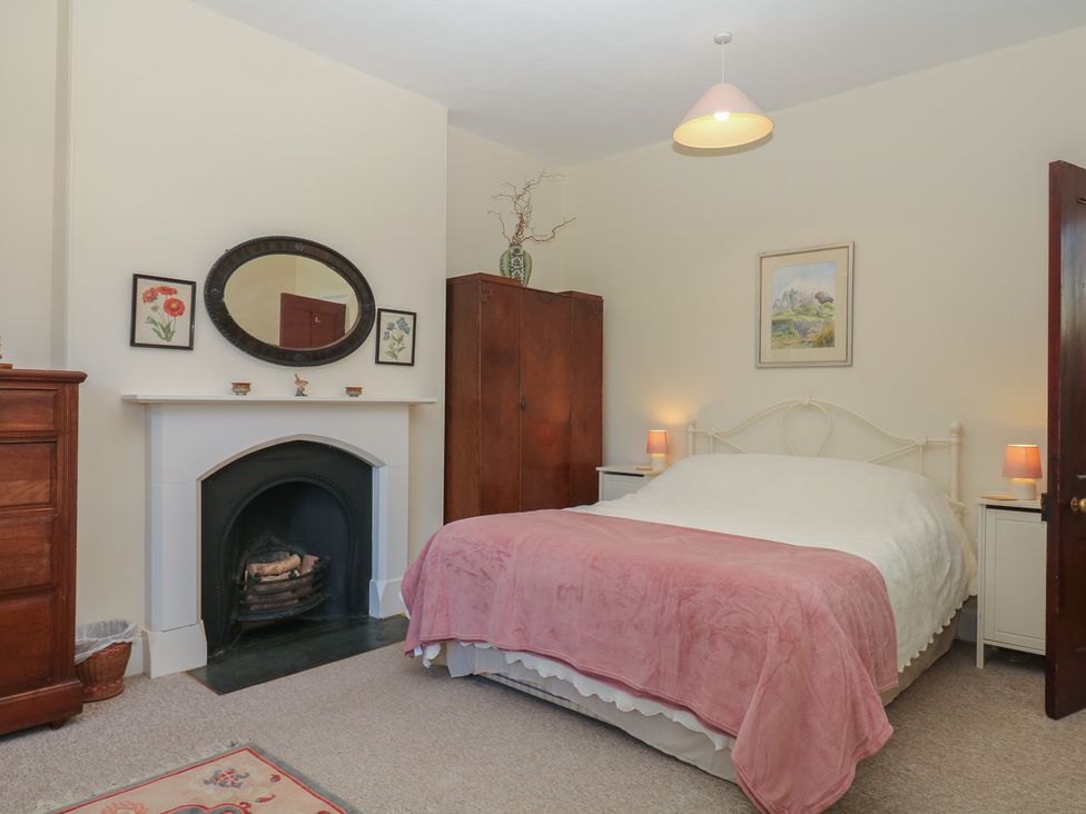 A bedroom with a bed, wardrobe, and fireplace at Lukesland Wing in Ivybridge