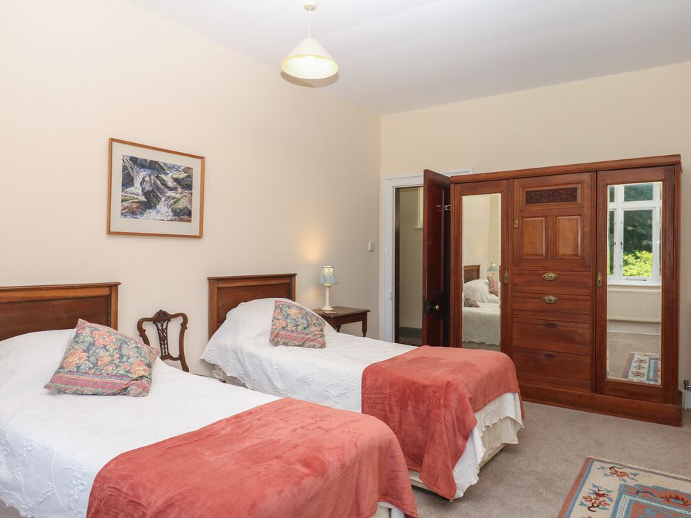 A bedroom with two beds and a wardrobe at Lukesland Wing in Ivybridge