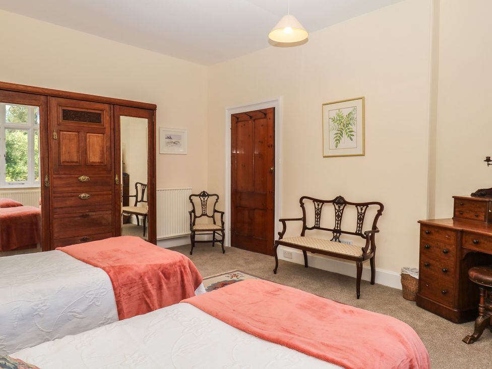 A bedroom with two beds and a wardrobe at Lukesland Wing in Ivybridge