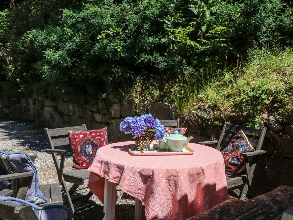 An outdoor seating area with a table, chairs, and flowers at Lukesland Wing in Ivybridge
