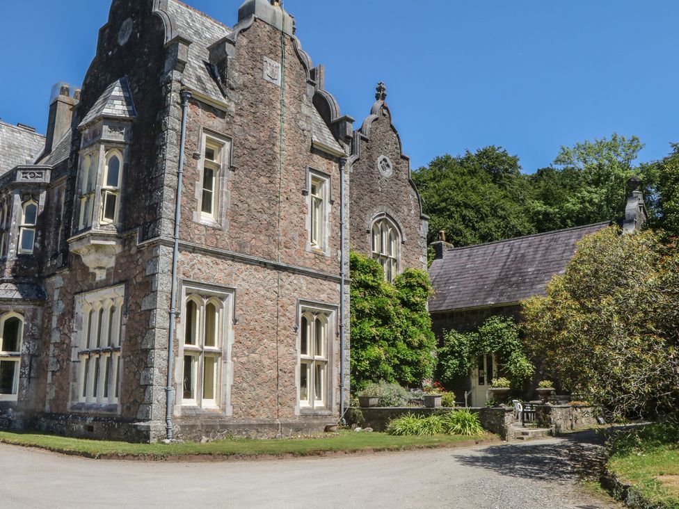 A stone building with windows and greenery at Lukesland Wing in Ivybridge