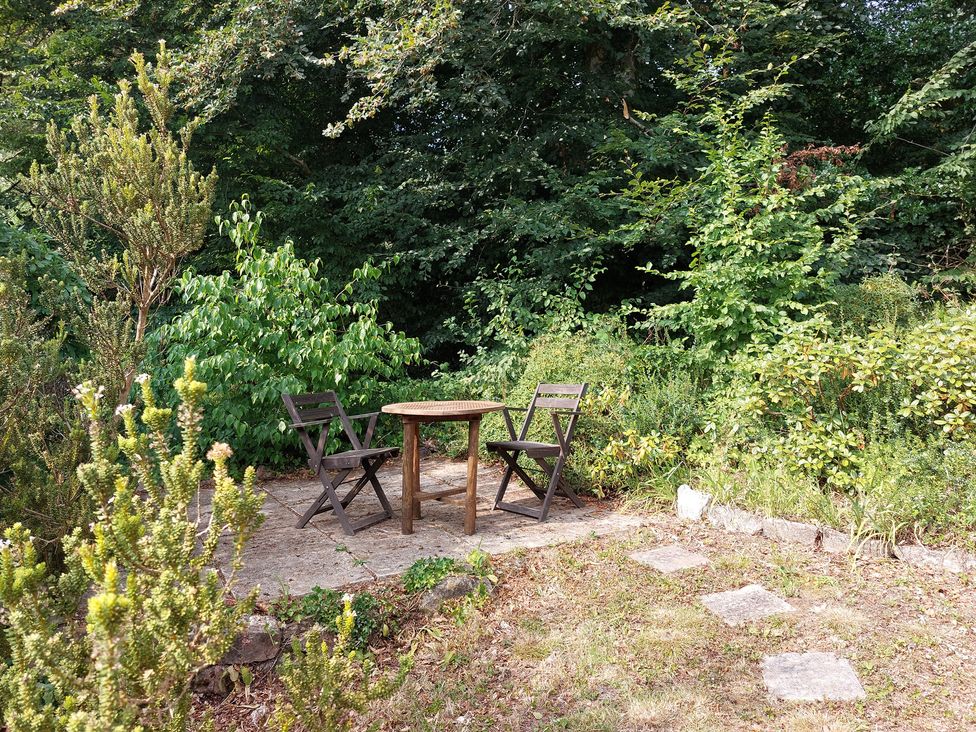 A table and chairs surrounded by plants in a garden at Lukesland Wing near Ivybridge