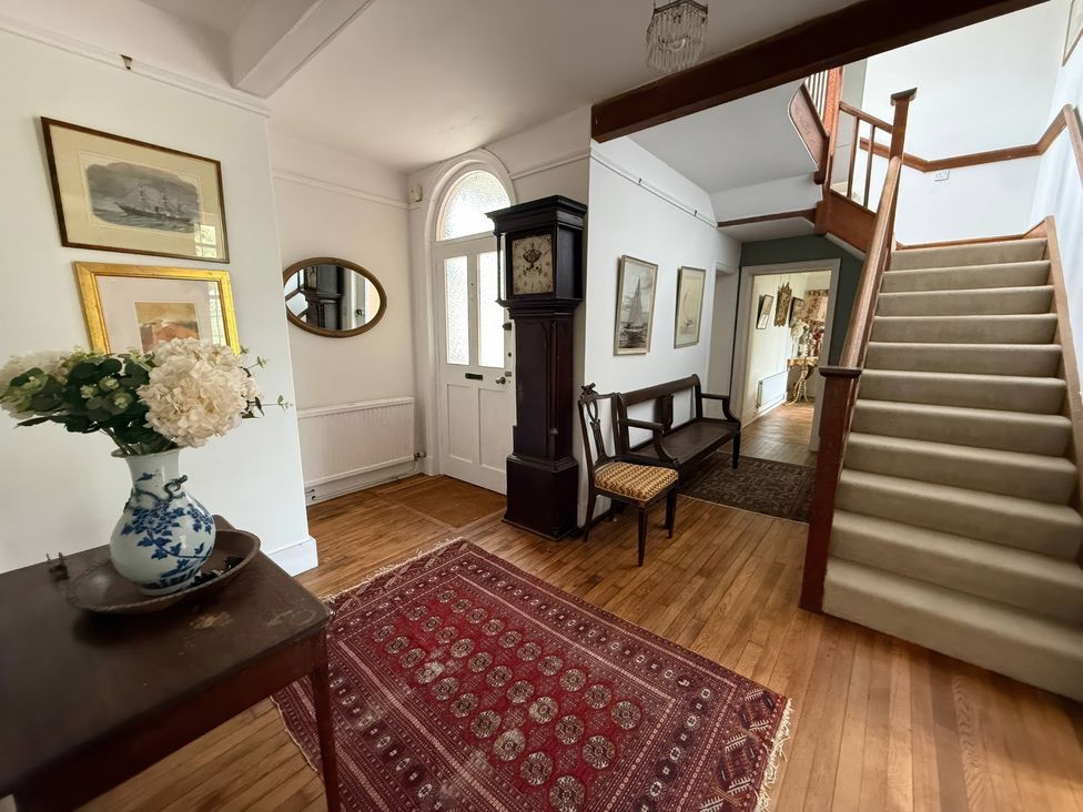 A hallway with a staircase and table displaying flowers at Avenue Road in Lymington