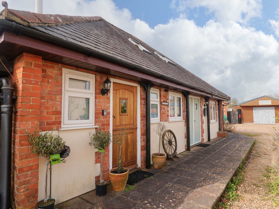 A front view of a brick house with plants and a paved pathway at The Coach House in Dorchester