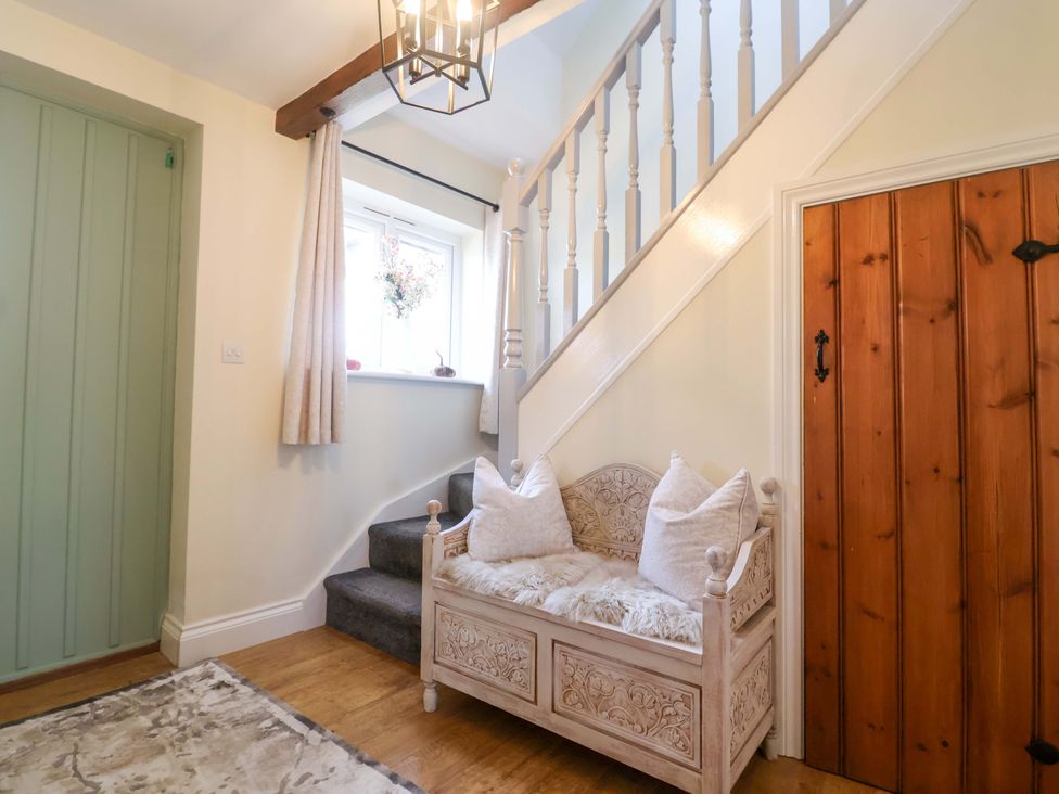 A hallway with a staircase and bench at The Coach House in Dorchester