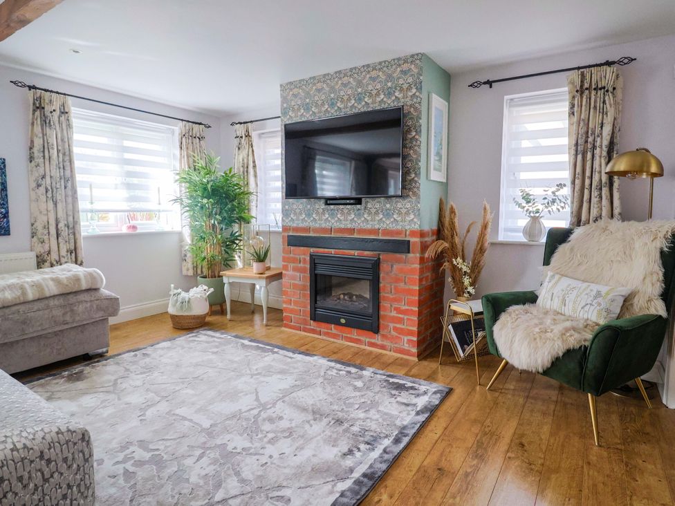 A living room with a fireplace and television at The Coach House Dorchester