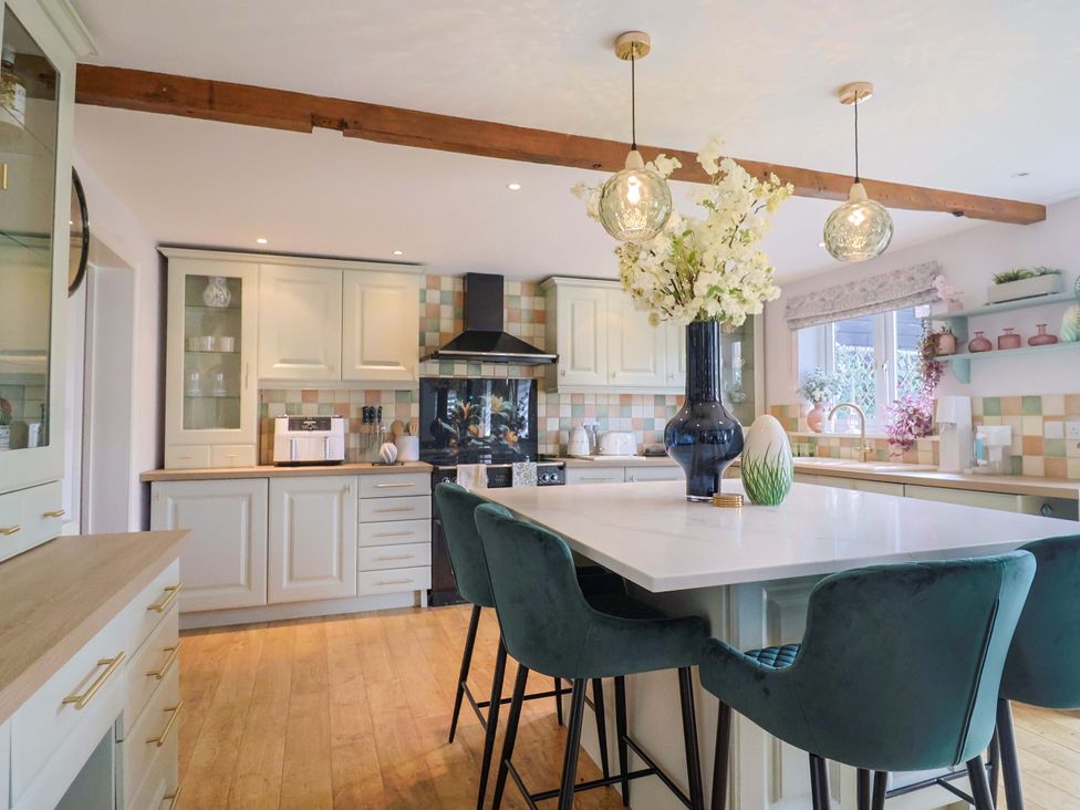 A kitchen with an island and bar stools at The Coach House in Dorchester