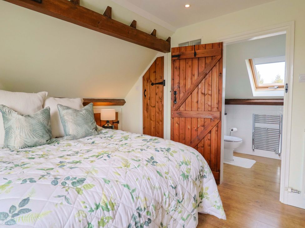 A bedroom with a bed and wooden doors at The Coach House in Dorchester