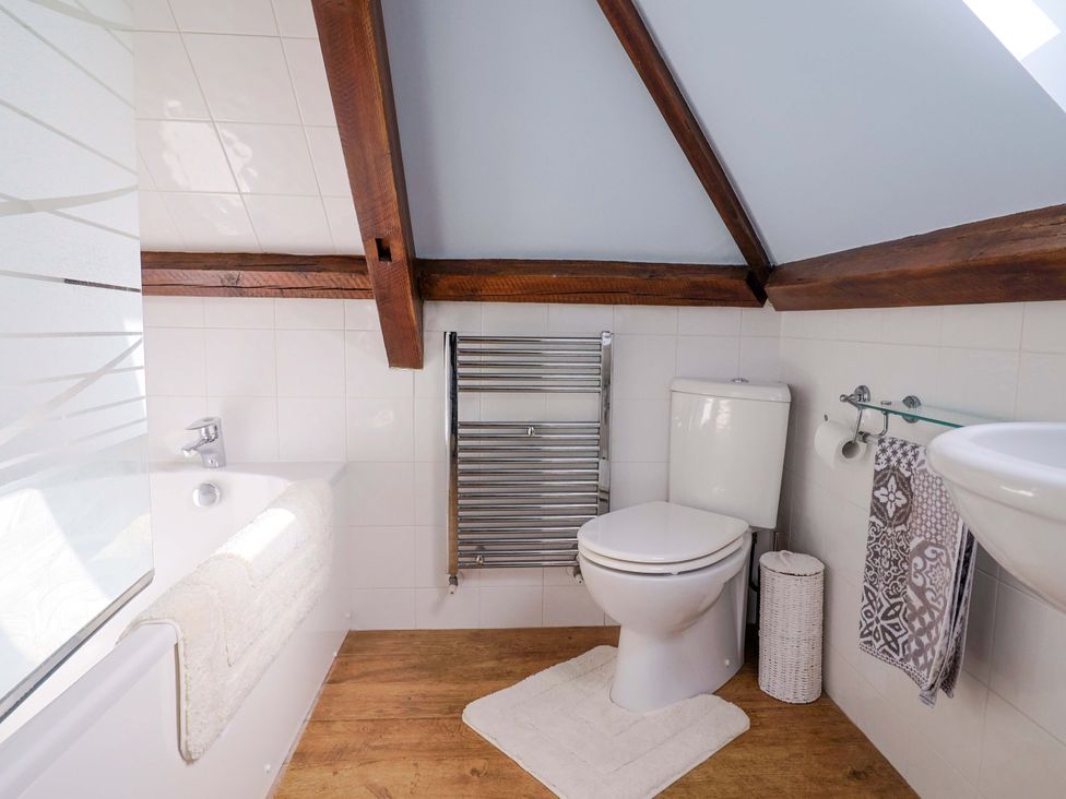 A bathroom with a shower, bathtub, toilet, towel rail, and sink at The Coach House in Dorchester