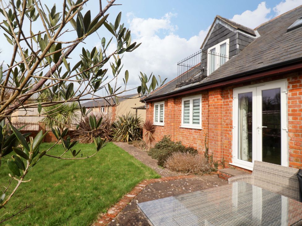 A garden view with greenery and a brick house at The Coach House in Dorchester
