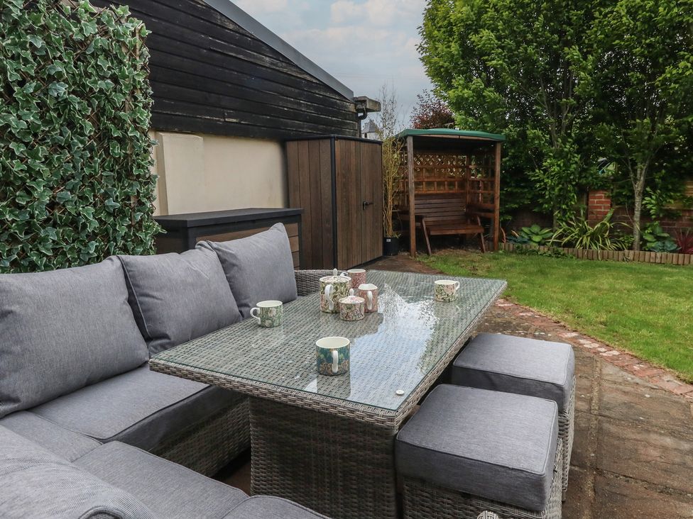 A garden with a couch and table set at The Coach House Near Charminster