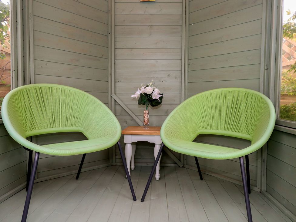 A snug with two green chairs and a table with flowers at The Coach House Near Charminster