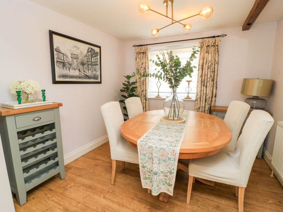 A dining room with a round table and chairs at The Coach House Near Charminster