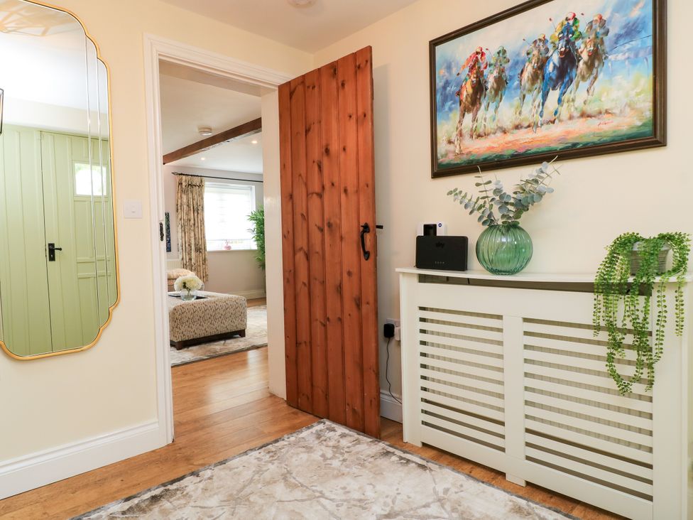 A hallway featuring a wooden door and a mirror at The Coach House Near Charminster