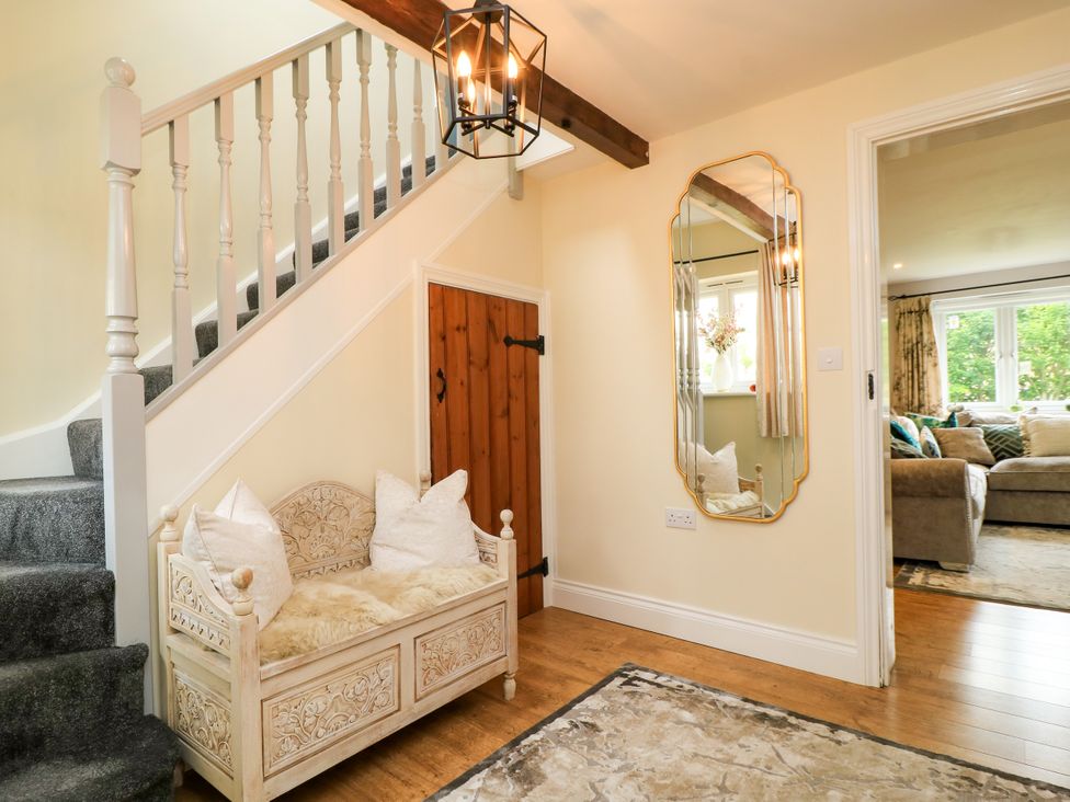A hallway with a staircase and a decorative mirror at The Coach House Near Charminster