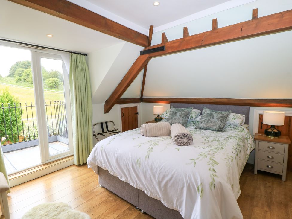 A bedroom with a bed, bedside tables, and a view at The Coach House near Charminster