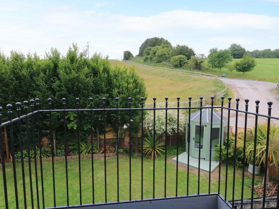 A garden with a greenhouse and trees at The Coach House near Charminster