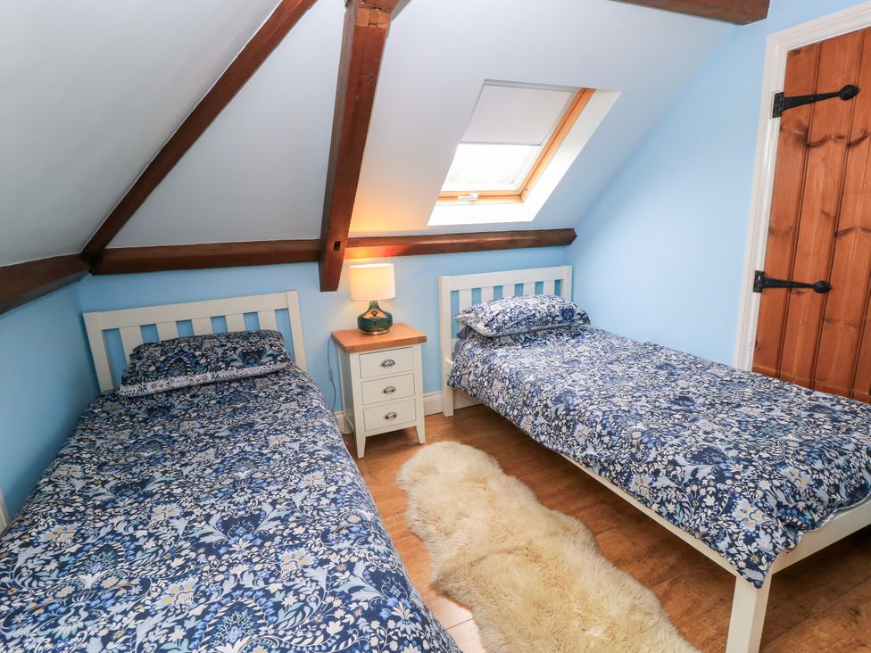 A bedroom with two beds and a nightstand at The Coach House Near Charminster