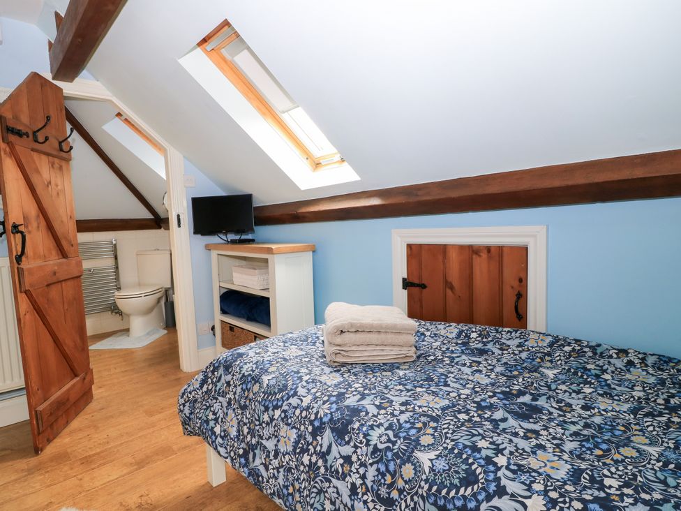 A bedroom with a bed and towels on a table at The Coach House near Charminster