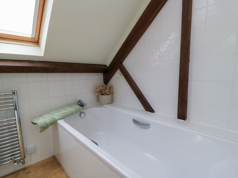 A bathroom with a bathtub and a window at The Coach House near Charminster