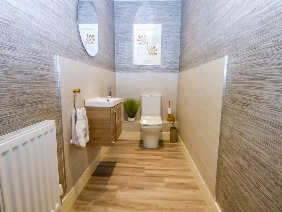 A bathroom with a sink, toilet, and mirror at 2 Glan Yr Aber, Colwyn Bay
