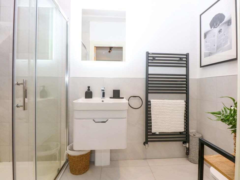 A bathroom with a sink, shower, and towel rail at 2 Glan Yr Aber in Colwyn Bay