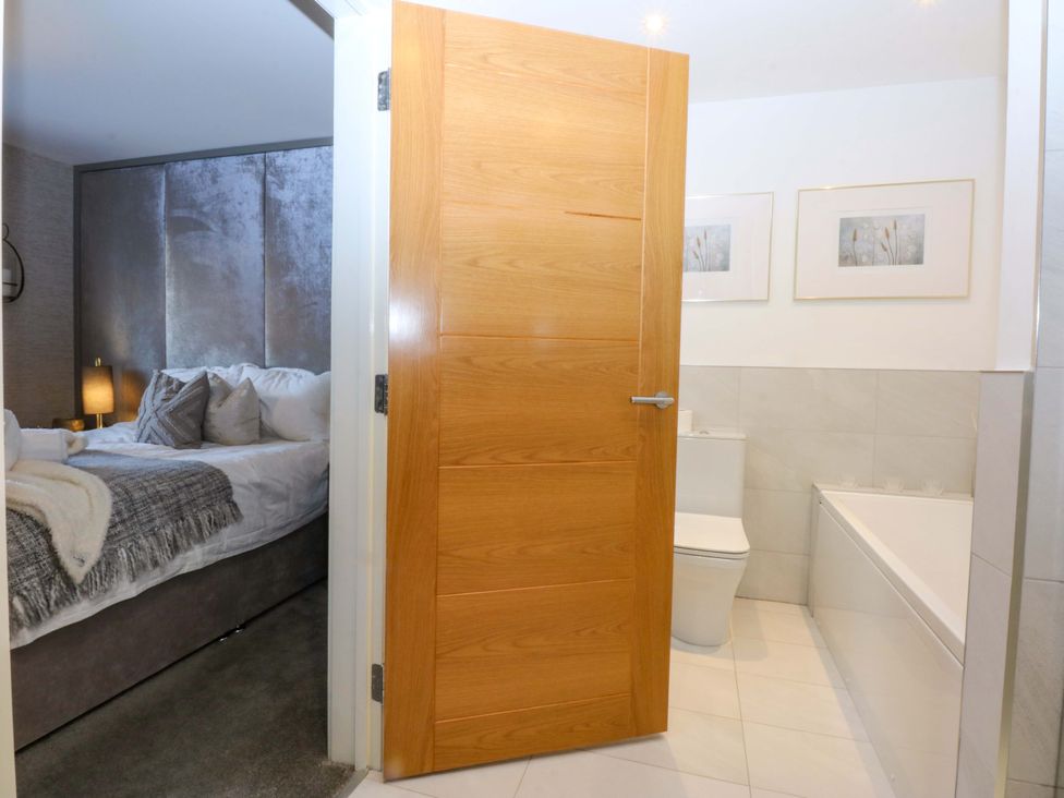 A bathroom with a toilet and bathtub near a bedroom at 2 Glan Yr Aber in Colwyn Bay