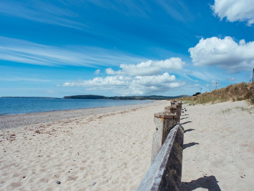 A beach with a wooden barrier near the water at Ty Pen in Nefyn