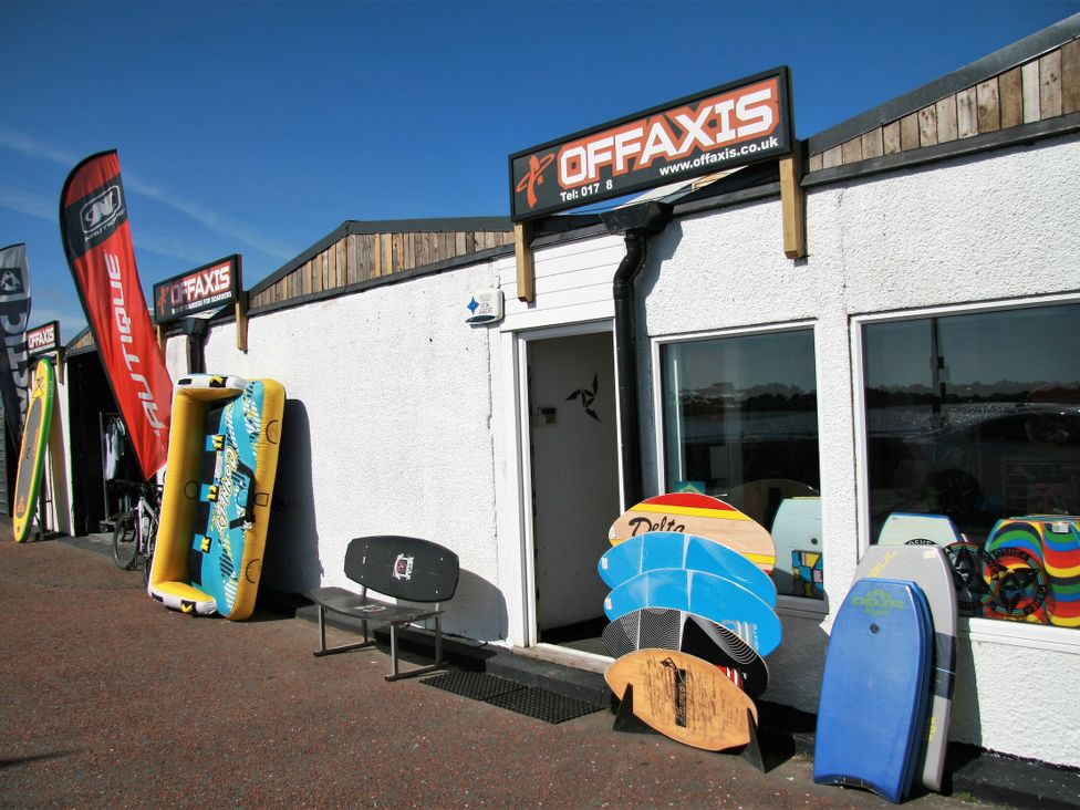 An outdoor shop with surfboards and water toys at Off Axis in Nefyn