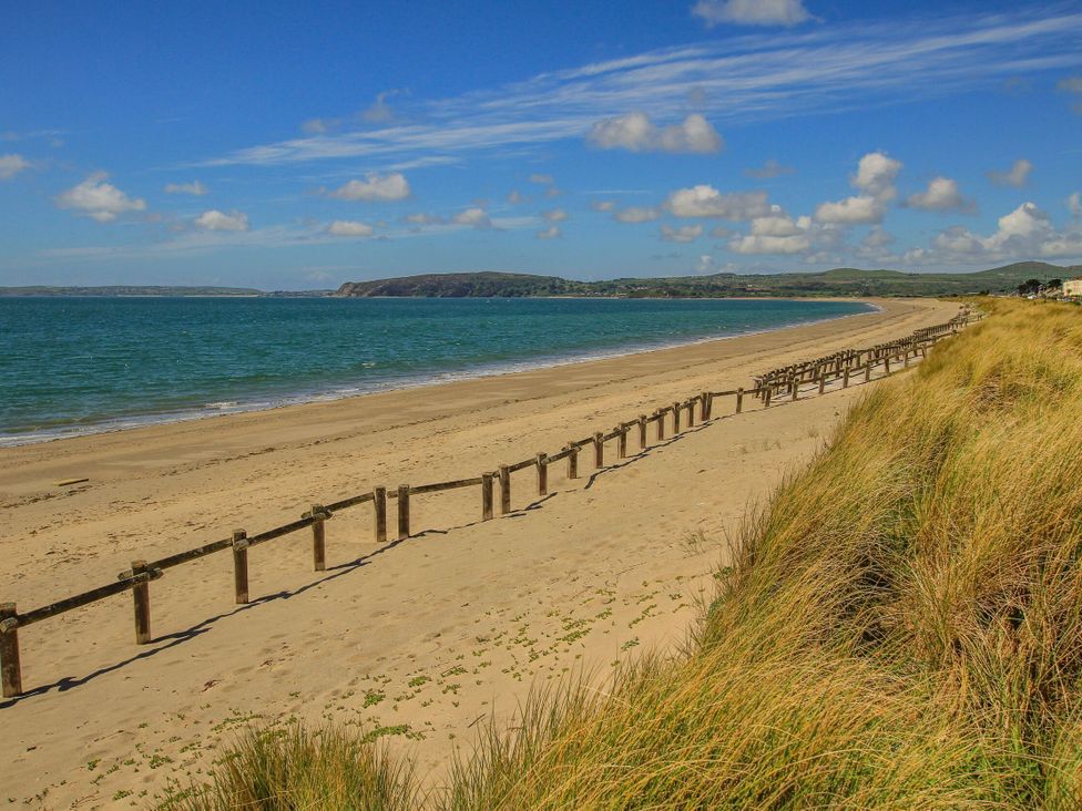 A beach with sand and a wooden fence at Ty Pen in Nefyn
