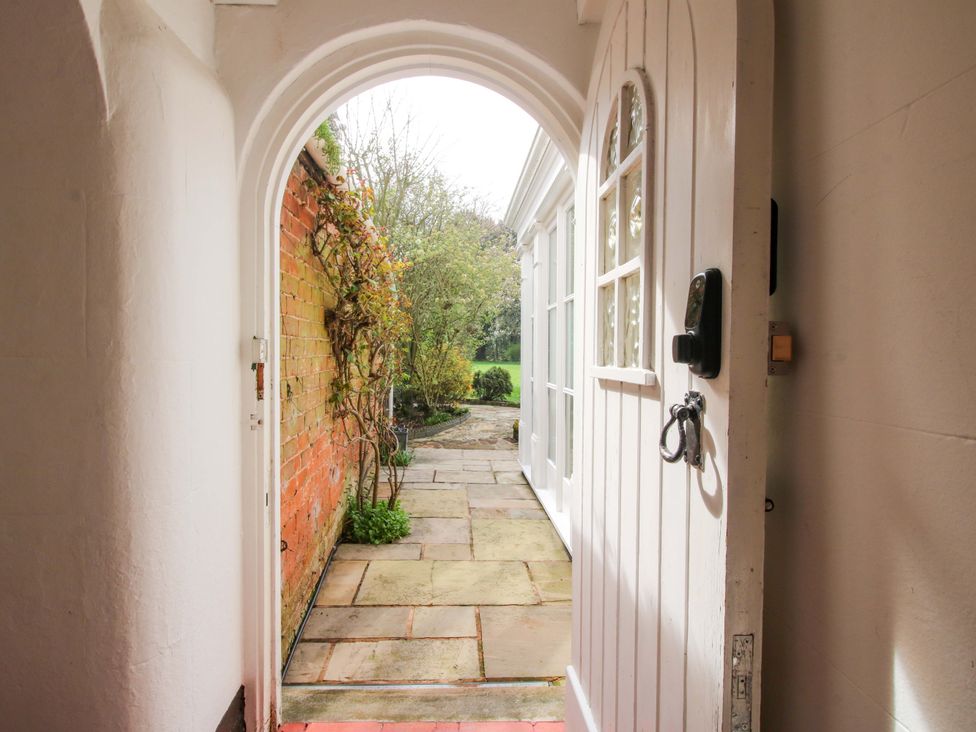 An entryway with a door leading to a pathway and garden at The Apartment at the Grey House in Albrighton