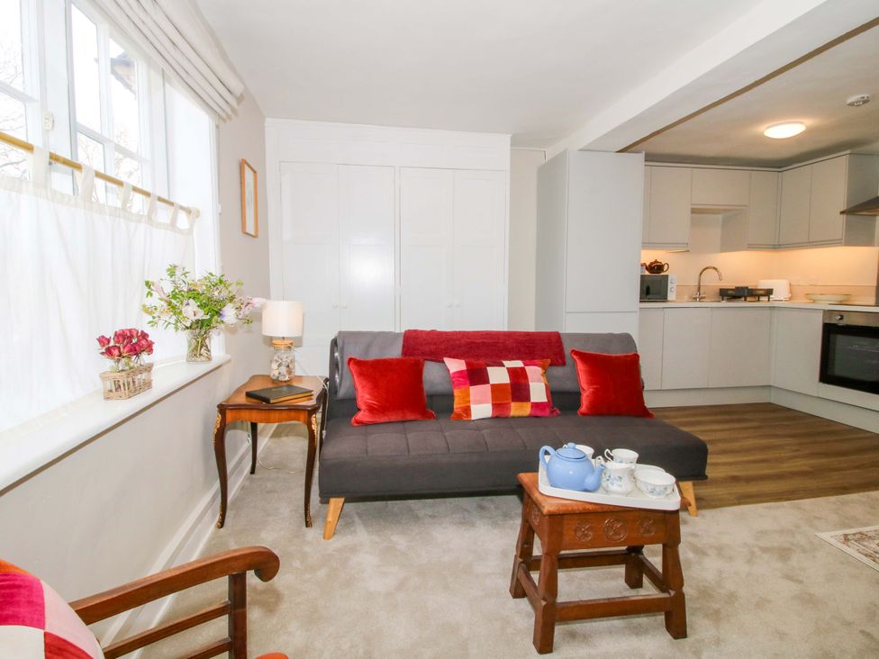 A living room with a couch and kitchen area at The Apartment at the Grey House in Albrighton