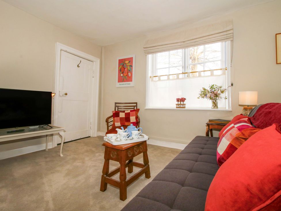 A living room with a TV, couch, and table at The Apartment at the Grey House in Albrighton