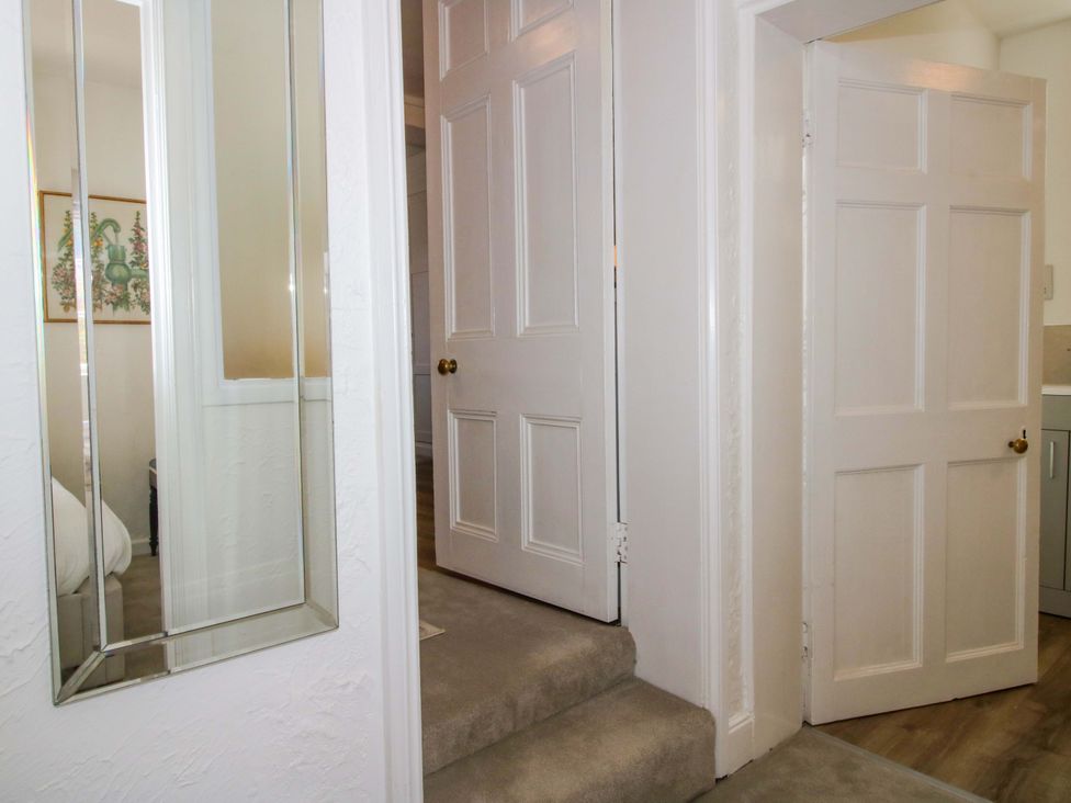 A hallway with a mirror and doors at The Apartment at the Grey House in Albrighton
