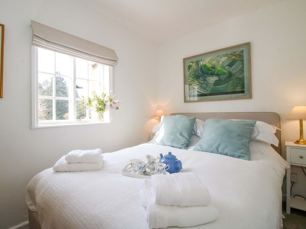 A bedroom with a bed, bedside table, and a vase of flowers at The Apartment at the Grey House in Albrighton