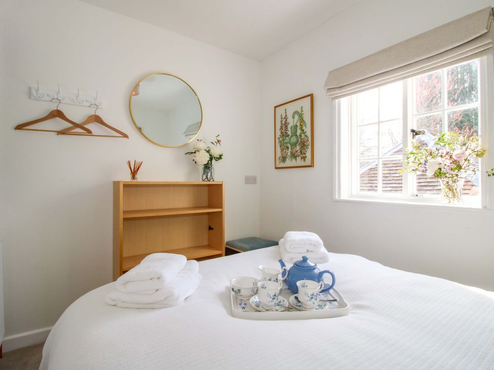 A bedroom with a bed, shelves, and a window at The Apartment at the Grey House in Albrighton