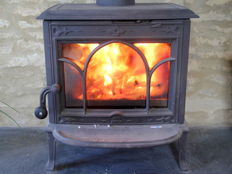 A wood stove with fire inside at Stanbridge Cottage in Malmesbury