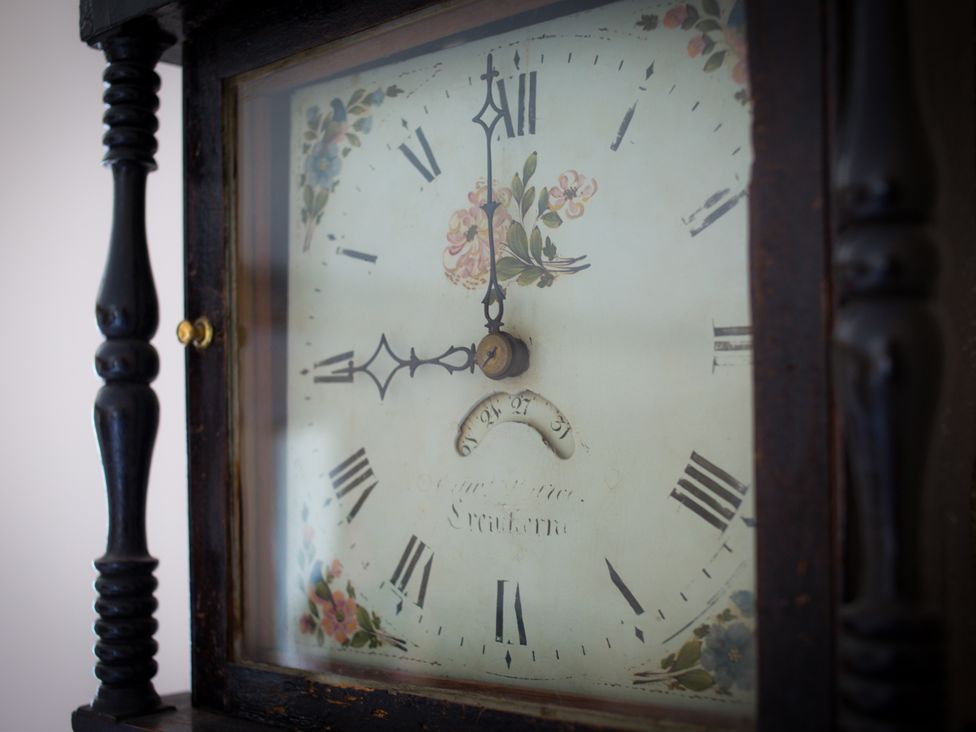A close-up of an antique clock with floral design at Stanbridge Cottage in Malmesbury