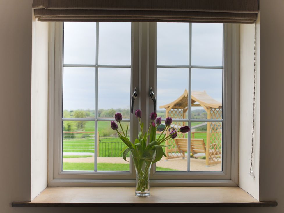 A window with a vase of tulips viewing a garden at Stanbridge Cottage in Malmesbury
