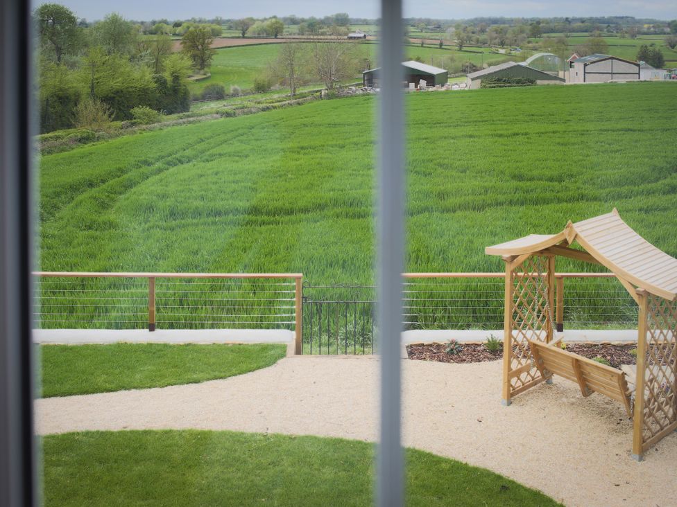 A view of a garden with a wooden structure and a field at Stanbridge Cottage in Malmesbury