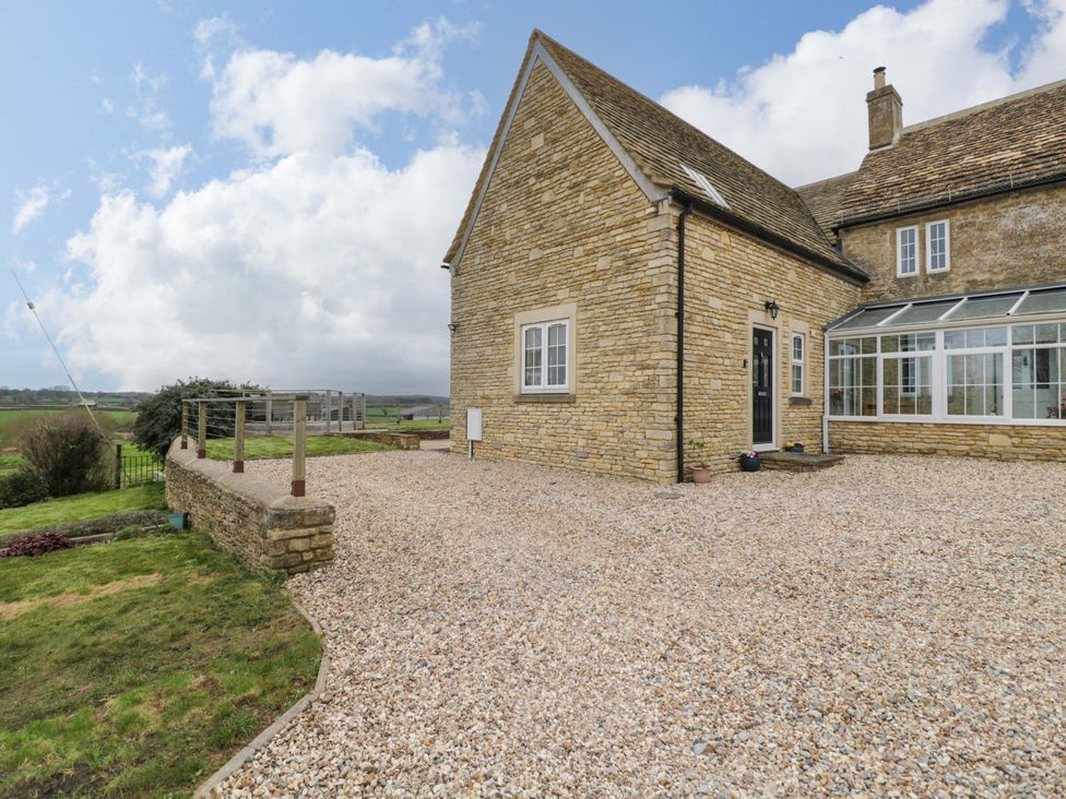 A house with a gravel driveway and garden at Stanbridge Cottage in Malmesbury