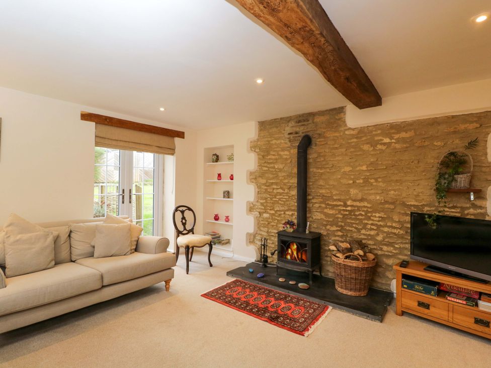 A living room with a sofa, television, and fireplace at Stanbridge Cottage in Malmesbury