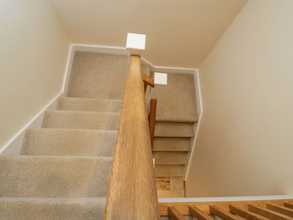 A staircase with a wooden handrail at Stanbridge Cottage Malmesbury