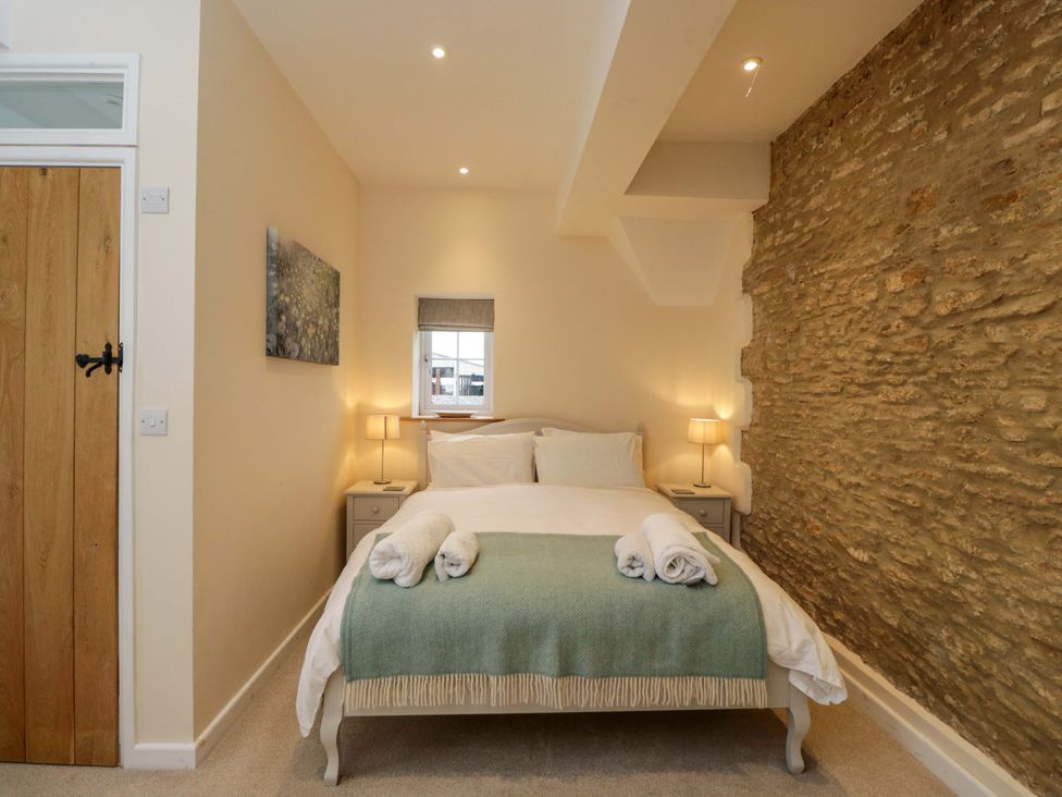 A bedroom with a bed and lamps at Stanbridge Cottage in Malmesbury