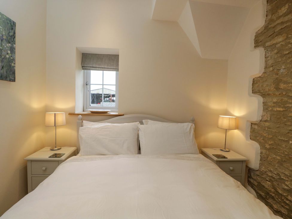 A bedroom with a bed and lamps at Stanbridge Cottage Malmesbury