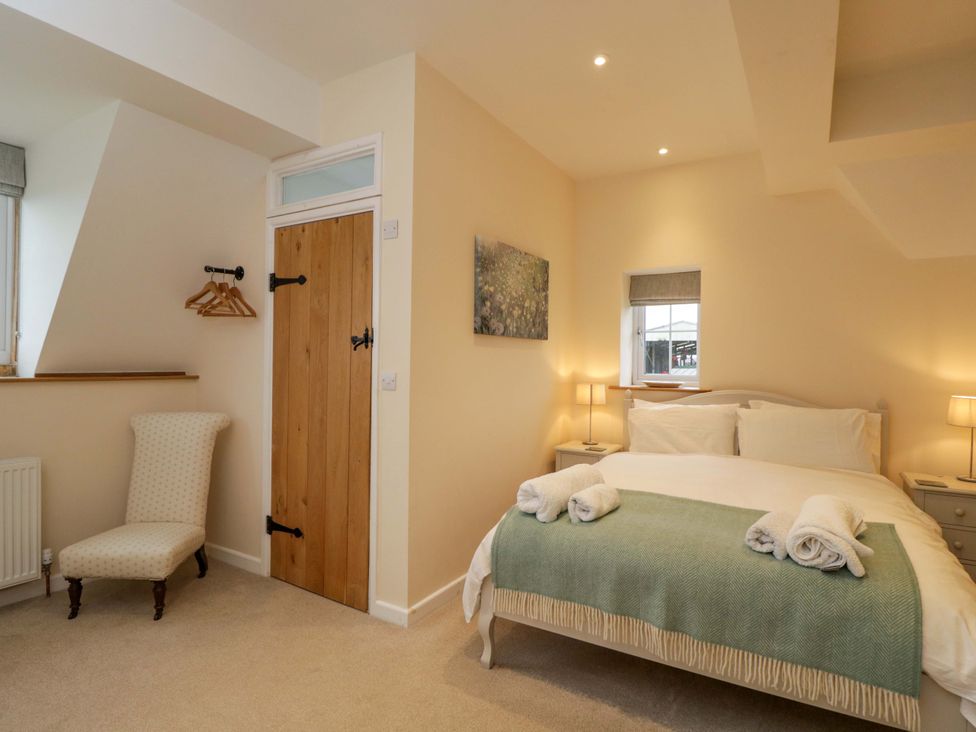 A bedroom with a bed and a chair at Stanbridge Cottage in Malmesbury