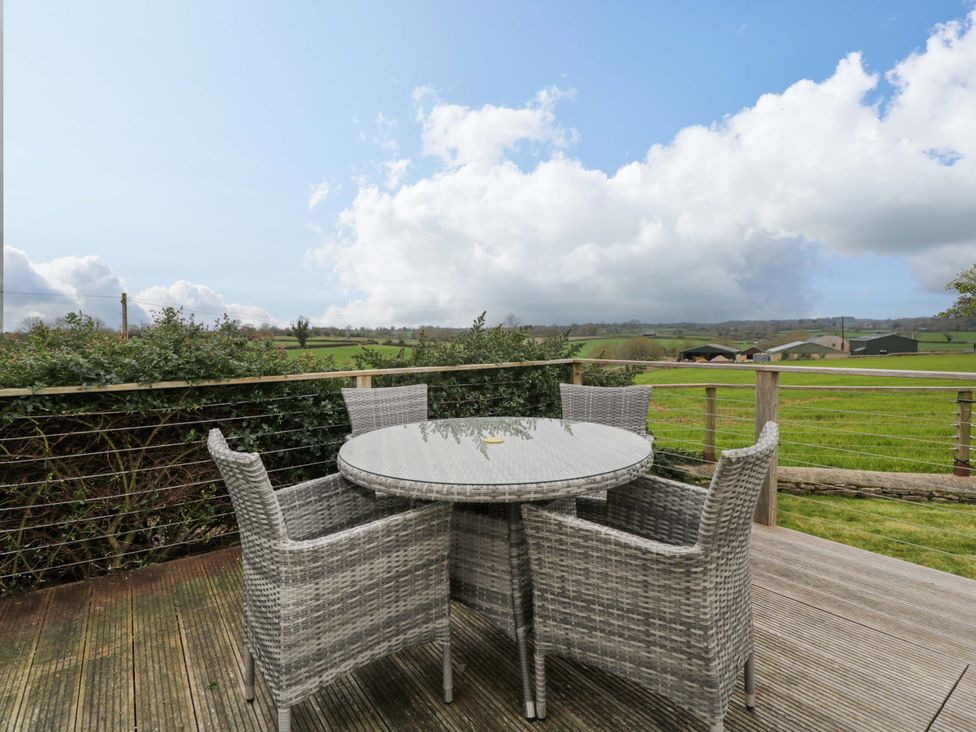 A deck with a table and chairs overlooking fields at Stanbridge Cottage in Malmesbury